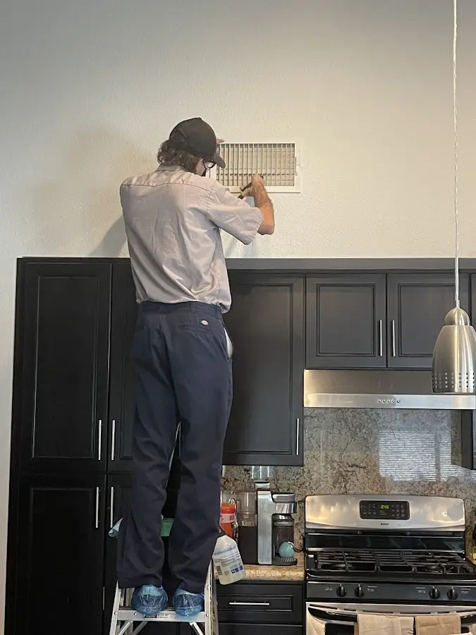 Technician inspecting an air vent during HVAC service in Long View